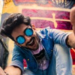 A lively portrait of a young man in urban streetwear, enjoying a vibrant city background.