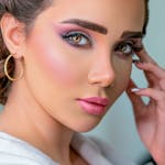 Close-up portrait of a woman with vivid makeup and gold hoop earrings, exuding elegance and style.